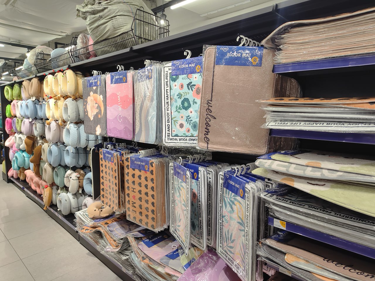 Отдел магазина с различными напольными ковриками и подушками для сидения на полках.