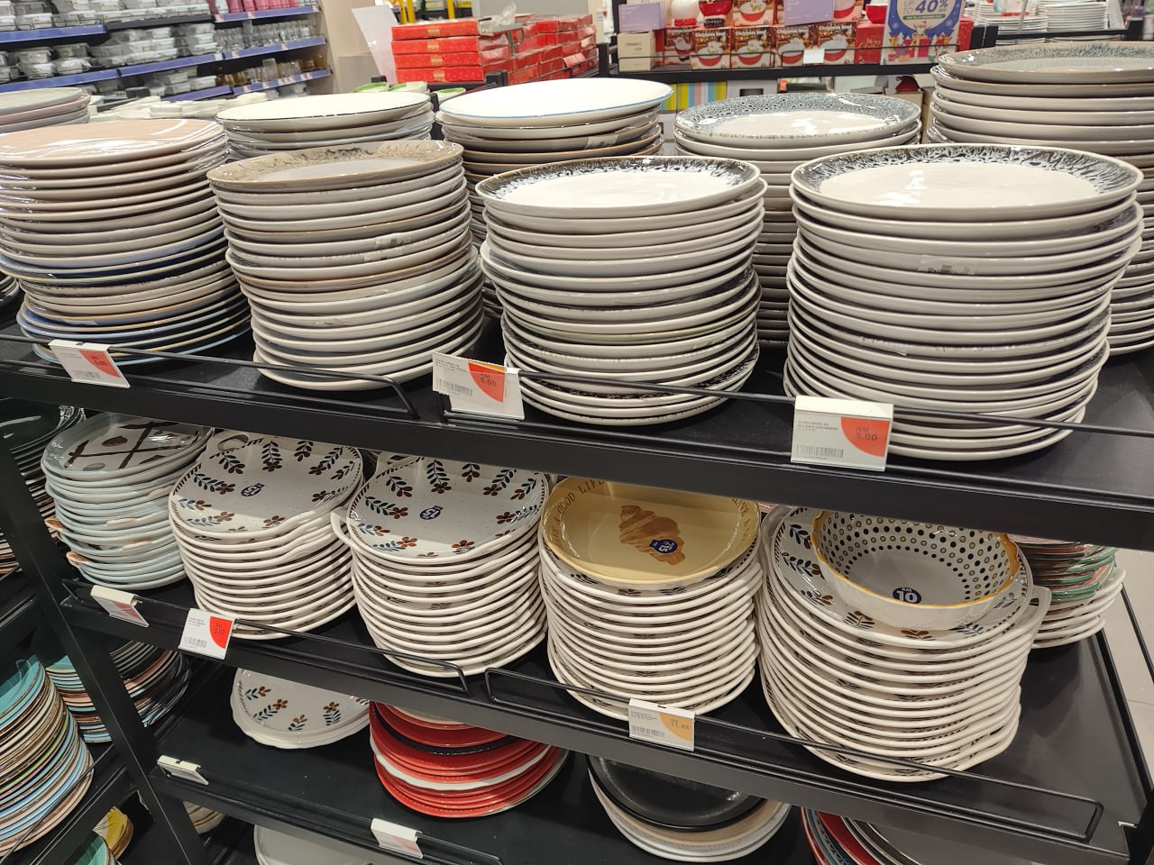 Полка с тарелками разного дизайна в торговом зале.