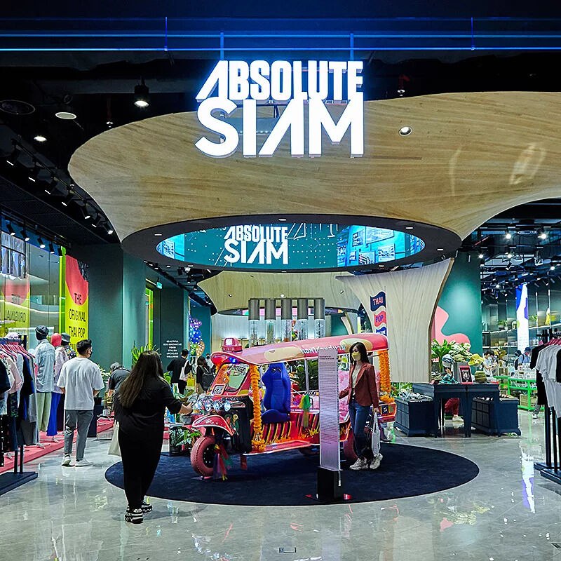 В центре изображения находится магазин Absolute Siam, который расположен в торговом центре Siam Paragon в Бангкоке, Таиланде. В магазине продается широкий ассортимент одежды, аксессуаров и других товаров. В