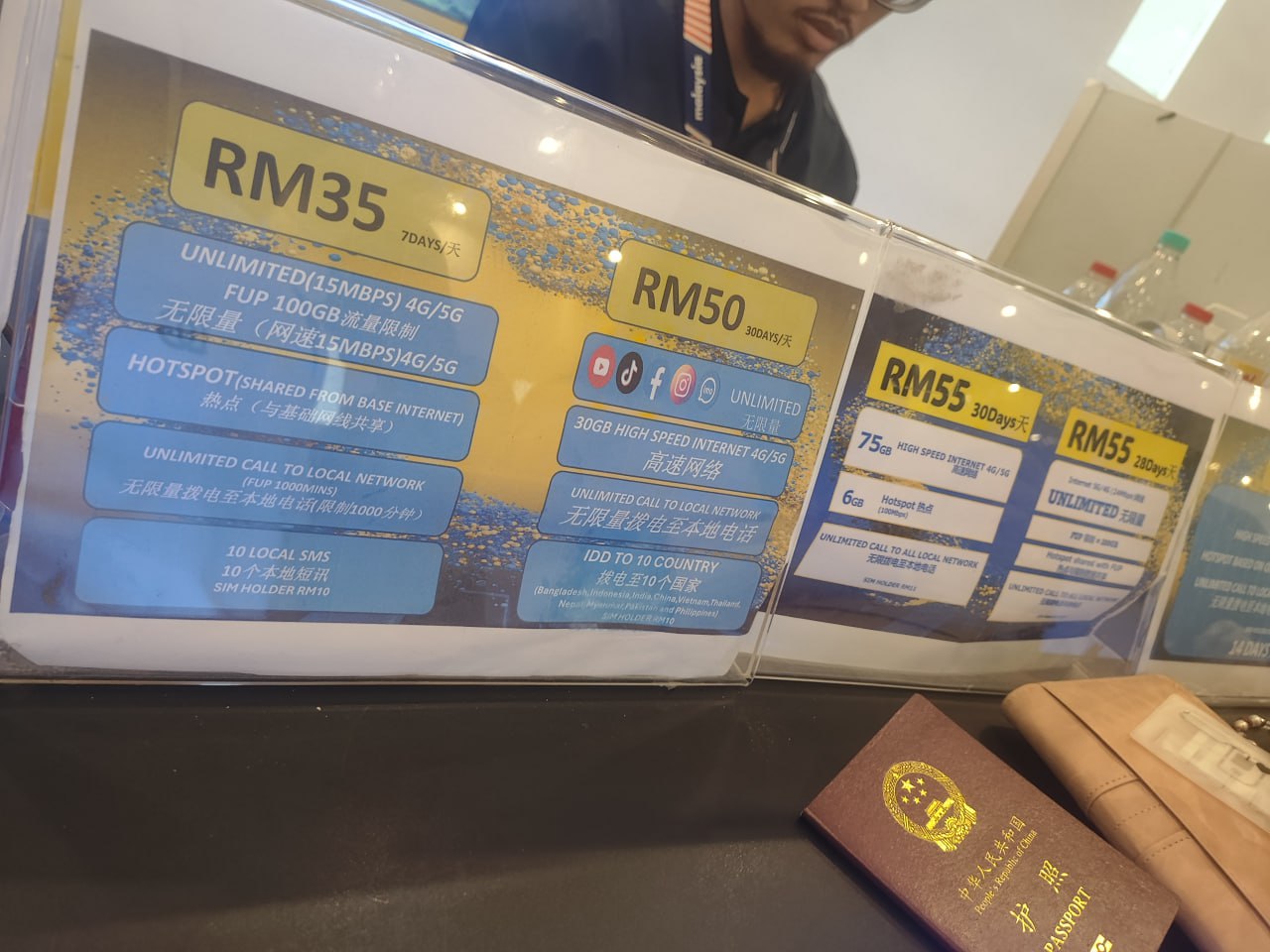 The image shows a table with a sign on it, featuring a list of prices and services offered by a company. The sign is divided into three sections, each with a different price point and corresponding services. The prices are listed in Malaysian Ringgit (RM) and range from RM35 to RM55. The services include